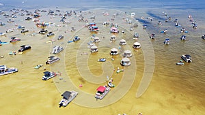 Crowd of people at Crab Island in Destin, Florida during low tide with brown brackish water, busy pontoons, jet skis, paddleboards