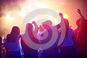 Crowd, people dancing at concert or music festival from back, neon lights and energy at live event. Dance, fun and group