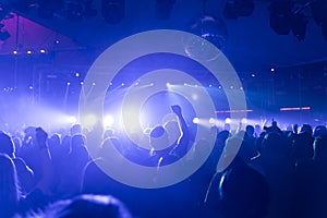 A crowd of people partying in a disco club, light and lasers and foggy environment