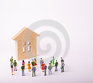 A crowd of people standing and looking at a wooden house on a white background. Buying and selling of real estate, rent.