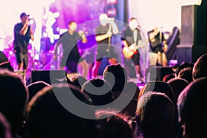 A crowd of people watching a musical group performing on stage