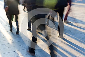 Crowd on the sidewalk at sunset with long shadows