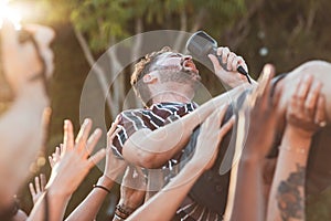 Crowd, surfing and man singing at party, outdoor music festival or social gathering. Microphone, energy and male singer