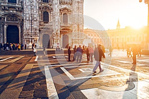 Crowd of tourist people walking in center of old town near Duomo in Milan, Italy at sunset time.