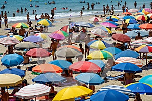 Crowded beach scene with numerous people and colorful umbrellas, A crowded beach dotted with colorful umbrellas and sunbathers