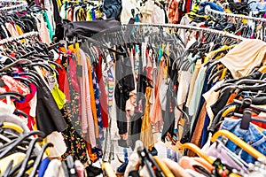 Crowded clearance section in a clothing store, with various colorful garments placed tightly on racks in no particular order; fast