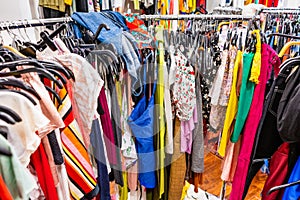 Crowded clearance section in a clothing store, with various colorful garments placed tightly on racks in no particular order; fast