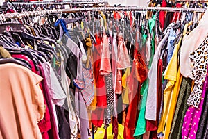 Crowded clearance section in a clothing store, with various colorful garments placed tightly on racks in no particular order; fast