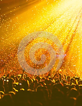 A crowded concert hall with scene stage orange and yellow lights, rock show performance, with people silhouette, colourful