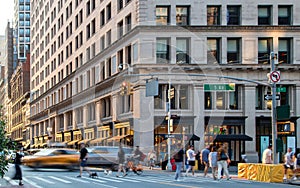 Crowded intersection with busy people and cars in motion at the corner of Fifth Avenue and 23rd Street in New York City