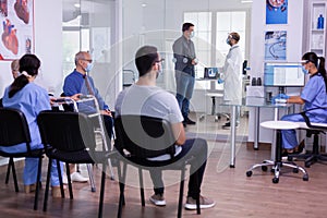 Crowded new normal hospital waiting room with patients sitting on chairs photo