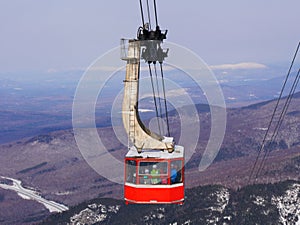 Crowded ski gondola and snow mountains background