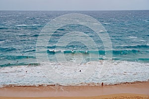 Crowded surfers riding Oahu Island beach waves