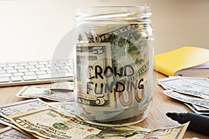Crowdfunding written on a jar with dollars.