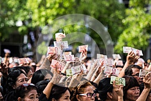 Crowds of mourners hold Thai cash for show picture of King Bhumibol during mourning ceremony