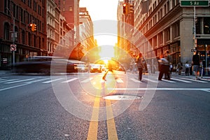 Crowds of people and cars in motion through the busy intersection on 5th Avenue and 23rd Street in New York City with sunlight in