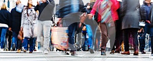 Crowds of people in motion blur crossing a city street