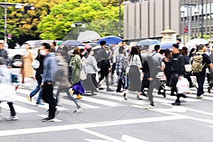 crowds of people crossing a street in Tokyo, Japan, while it is raining