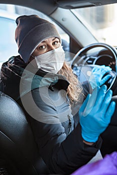 Crowdsourced taxi driver looking at the passenger wearing a facemask and latex gloves, asking to put mask on face