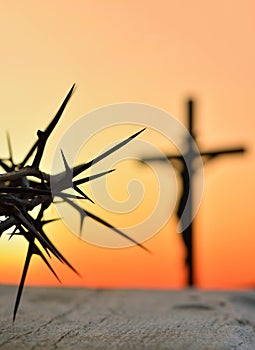 Crown of thorns of Jesus Christ against silhouette of catholic cross at sunset background