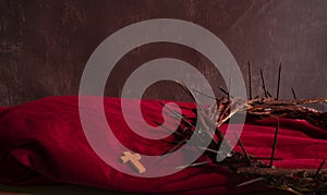 Crown of thorns of Jesus Christ with a small cross on a red cloth