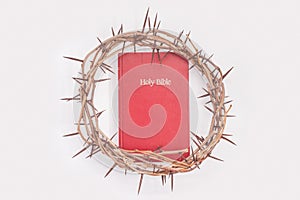 Crown of thorns and red bible isolated on white