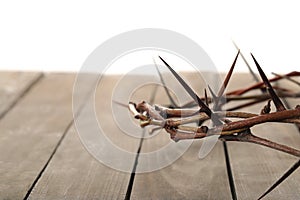 Crown of thorns on wooden table against white background, closeup with space for text. Easter attribute