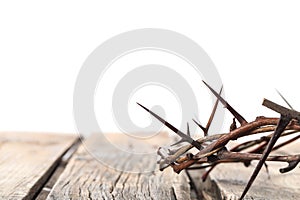 Crown of thorns on wooden table against white background, closeup with space for text. Easter attribute