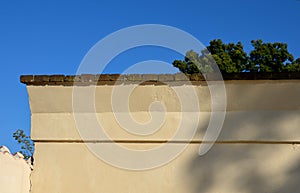 Crown wall, garden fence. fired bricks protect the low thick plastered wall of yellow color. wall in the shape of an arch and a br