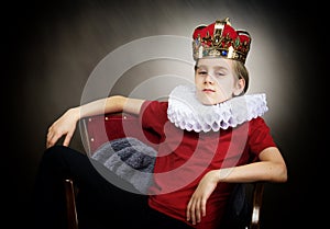 Crowned boy sitting in an armchair