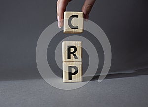 CRP - C-Reactive Protein Test symbol. Wooden cubes with word CRP. Doctor hand. Beautiful grey background. Medical and C-Reactive