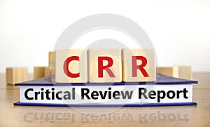 CRR critical review report symbol. Concept words CRR critical review report on wooden cubes on book on a beautiful white