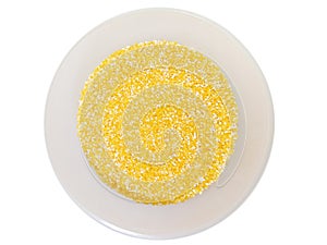 Cruched yellow sweet corn cereal in a white plastic bowl top view on a white background.