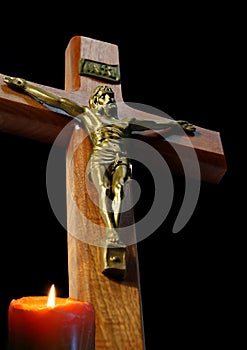 Crucifix with candle burning on black background