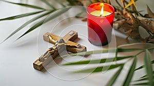 Crucifix with figure of Jesus, red candle and palm leaves on white background