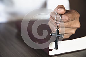 The crucifix in human hands rests on the Bible. Concepts for the study of Christians, Christianity, Catholicism, God, Heaven,