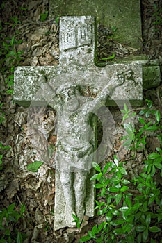 The crucifixion of Jesus Christ. Very old and ancient stone destroyed statue in the grass. Vertival image