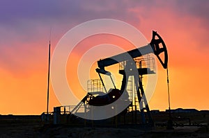 Crude oil pump jack at oilfield on atmospheric sunset backround. Fossil crude output and fuels oil production. Oil drill rig and