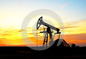 Crude oil pump jack at oilfield on atmospheric sunset backround. Fossil crude output and fuels oil production. Oil drill rig and