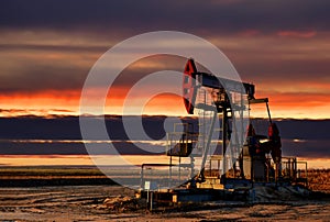 Crude oil pump jack at oilfield on atmospheric sunset backround. Fossil crude output and fuels oil production. Oil drill rig and