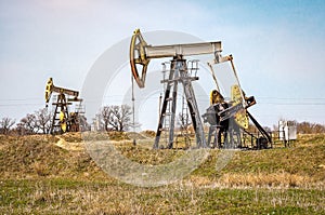 Crude oil pump jack at oilfield. Fossil crude output and fuels oil production. Oil drill rig and drilling derrick