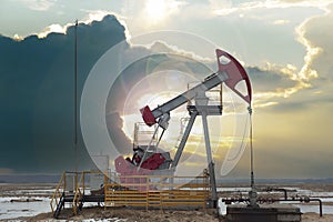 Crude oil pump jack at oilfield on sunset backround. Fossil crude output and fuels oil production. Oil drill rig and