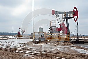 Crude oil pump jack at oilfield on sunset backround. Fossil crude output and fuels oil production. Oil drill rig and