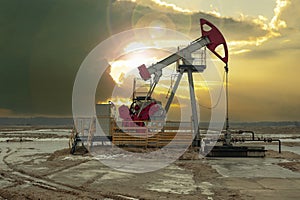 Crude oil pump jack at oilfield on sunset backround. Fossil crude output and fuels oil production. Oil drill rig and