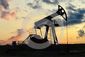 Crude oil pump jack at oilfield on sunset backround. Fossil crude output and fuels oil production. Oil drill rig and drilling