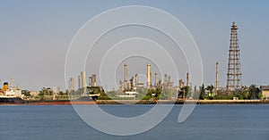 Crude oil refinery plant and many chimney with petrochemical tanker or cargo ship at coast of river on sky afternoon  bright day