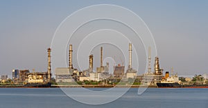 Crude oil refinery plant and many chimney with petrochemical tanker or cargo ship at coast of river on sky afternoon  bright day