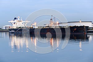 Crude oil supertanker ship moored to an oil terminal at twilight