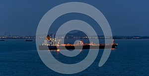 Crude oil tanker with navigation lights anchored in front of an oil storage terminal  at night