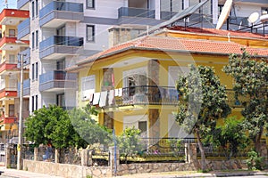 A crude onestory house against the backdrop of modern residential buildings, Alanya, Turkey, April 2021